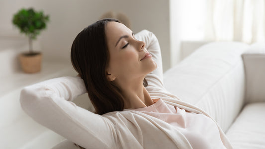A woman leans back on her sofa, breathing in clear air from her UVC sterilizer