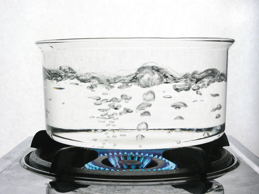 A clear pot of boiling water on a stovetop