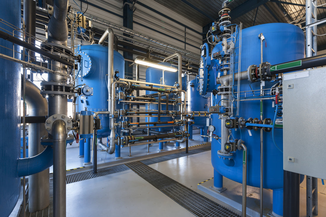 A mechanical room filled with several large industrial water filtering mechanisms and pipes