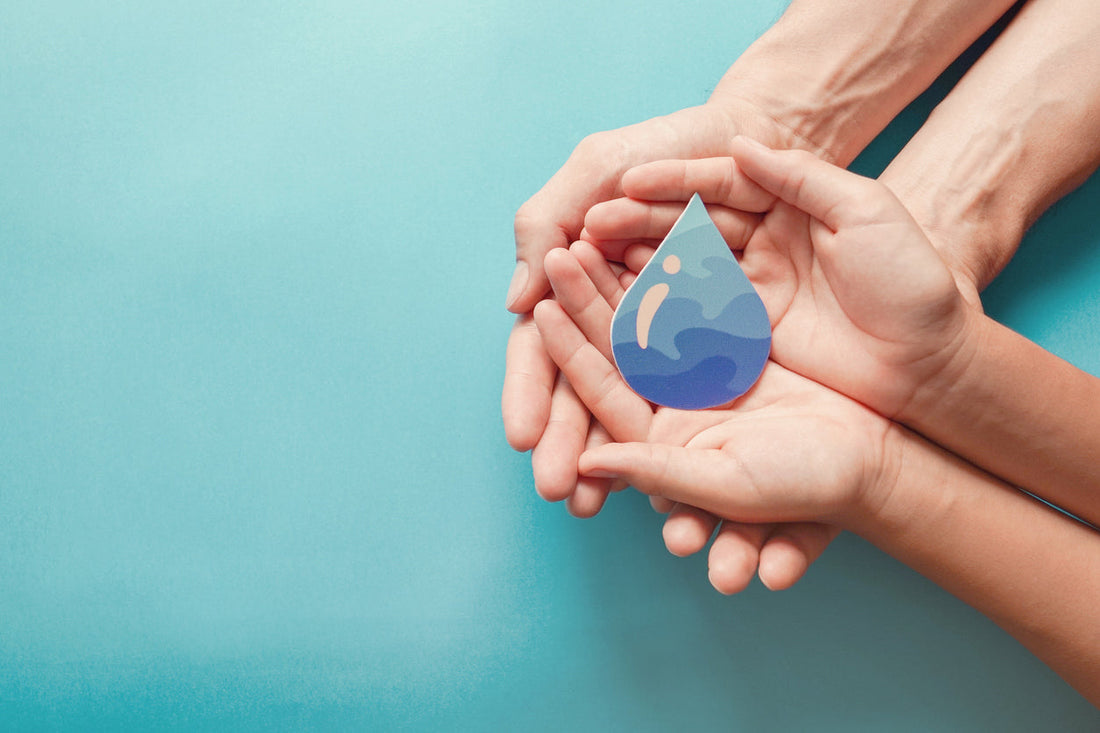 An adult and child hold a paper cut out of a water droplet promoting sustainable water solutions
