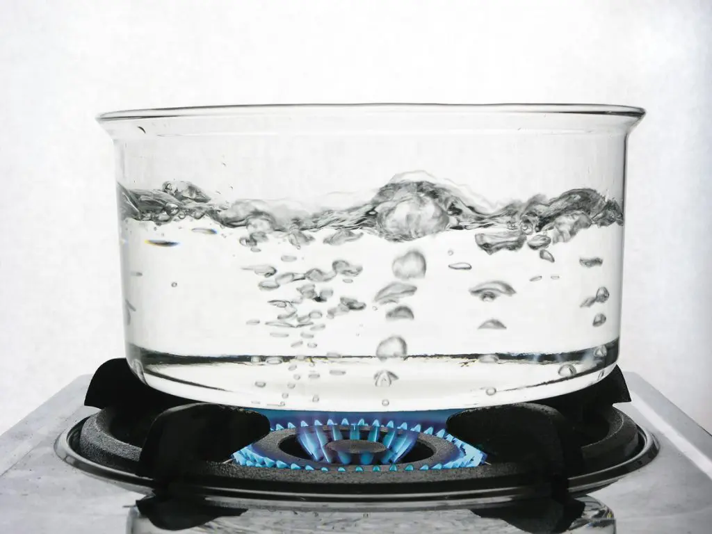 A clear pot of boiling water on a stovetop
