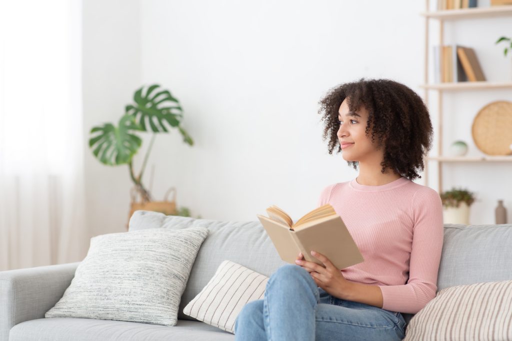 A woman sits with a book on her couch, breathing easy with a UVC sterilizer