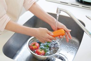 Someone washes vegetables in the kitchen sink