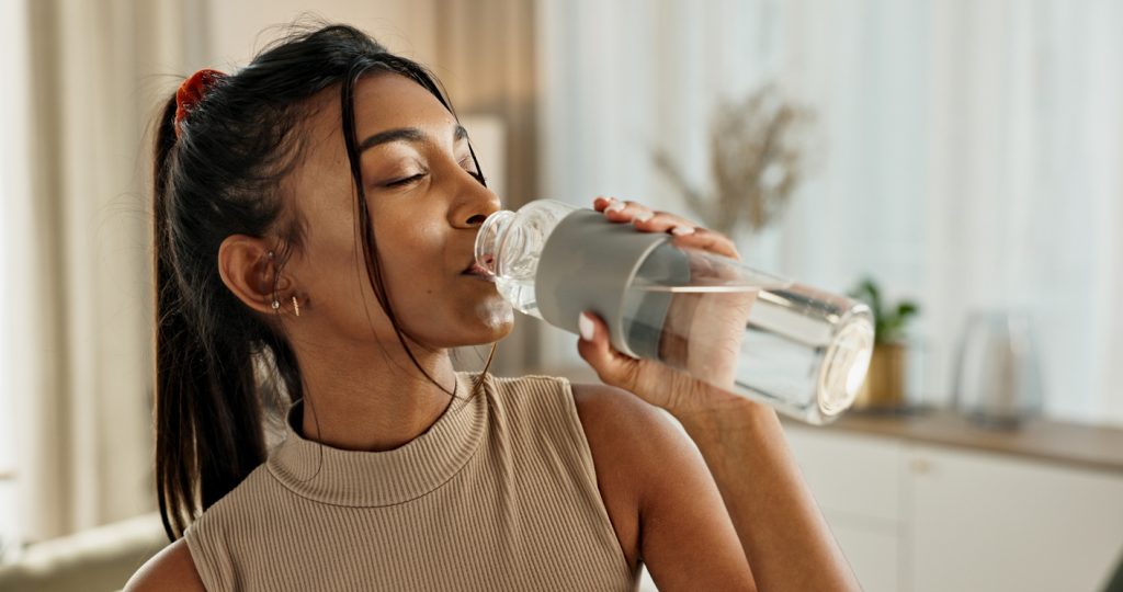 A woman drinks from a glass of pure, safe water taken from her home’s UV water filtration system